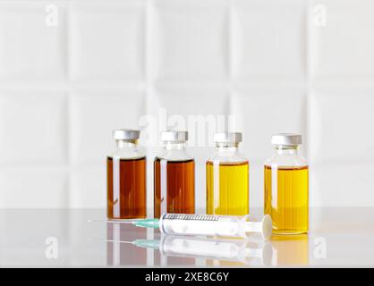 Gruppe von Glasflaschen mit injizierbarem Arzneimittel und einer Spritze auf weißem Labortisch. Weißer Hintergrund. Stockfoto