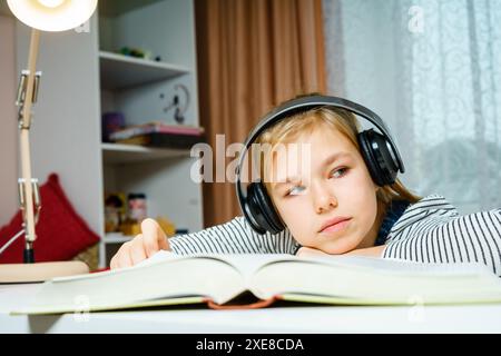 Teenager-Mädchen hört Hörbücher und macht Schulaufgaben, Lern- und Studentenkonzept Stockfoto