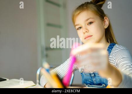 Schönes Mädchen, das zu Hause an ihrem Schulprojekt arbeitet, Bildungskonzept Stockfoto