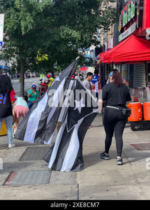 Die Frau trägt bei der Puerto Ricaner Day Parade im Sunset Park, Brooklyn, New York die schwarz-weiße Flagge des Widerstands. Stockfoto