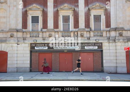 Die Bewohner der Nachbarschaft gehen an einer Kirche in der 116th Street und Fifth Avenue im Stadtteil Harlem von New York City vorbei. Stockfoto