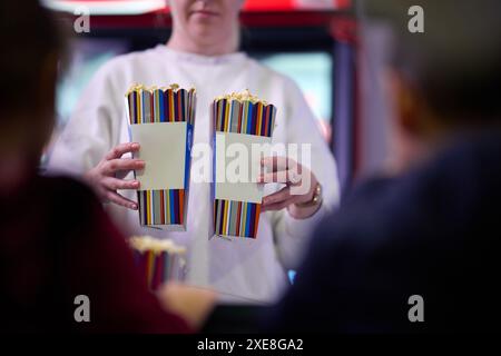 Ein Verkäufer steht vor dem Kino und hält frisches Popcorn, um es an Kinobesucher zu verkaufen, bevor sie das Kino betreten Stockfoto