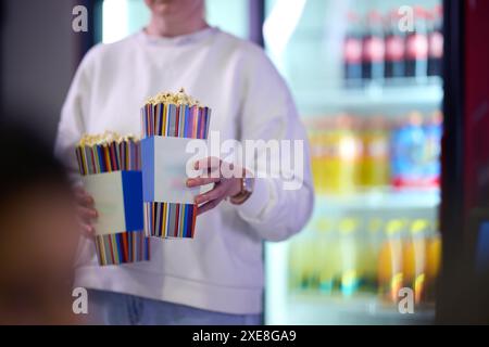 Ein Verkäufer steht vor dem Kino und hält frisches Popcorn, um es an Kinobesucher zu verkaufen, bevor sie das Kino betreten Stockfoto