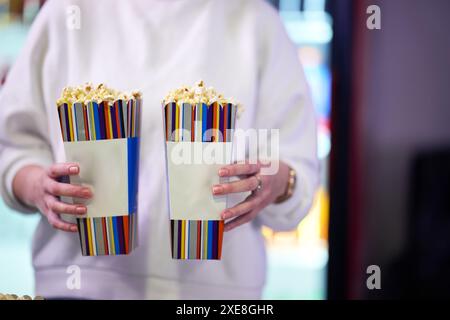 Ein Verkäufer steht vor dem Kino und hält frisches Popcorn, um es an Kinobesucher zu verkaufen, bevor sie das Kino betreten Stockfoto