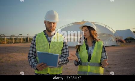 Ingenieurteam Kaukasischer Mann männlicher Kerl Inspektor Investor überprüft Bericht Clipboard Talk analysiert weibliche Mädchen Subunternehmer diskutieren reden Stockfoto
