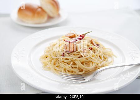Spaghetti aglio olio Peperoncino mit Brot auf dem Tisch Stockfoto