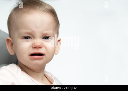 Ein Baby weint, während er auf einem Stuhl sitzt Stockfoto