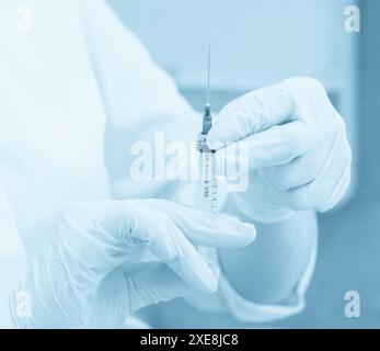 Medizinische Versorgung. Arzt mit Spritze, Injektion in Krankenhaus, blau Toning Stockfoto