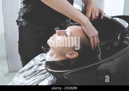 Haarstylist wäscht Haare von Yong-blonden Mädchen im Friseursalon vor dem Haarschnitt Stockfoto