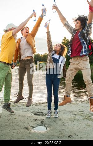Jubelnde Freunde feiern mit einem Toast am See Stockfoto