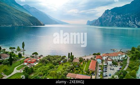 Torbole, Gardasee, Italien - 25. Juni 2024: Surferparadies Torbole am Gardasee von oben mit einer wunderschönen Bergkulisse und hellblauem Wasser. Torbole zieht jedes Jahr Athleten und Touristen wie Seeleute, Surfer und Windsurfer an. *** Surfer-Paradies Torbole am Gardasee von oben mit schöner Bergkulisse und strahlendem blauem Wasser. Torbole zieht Sportler und Touristen wie Segler, Surfer und Windsurfer jedes Jahr aufs neue an. Stockfoto