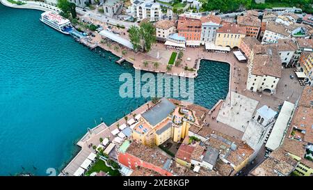 Riva del Garda, Gardasee, Italien - 25. Juni 2024: Malerische Altstadt von Riva del Garda mit ihren historischen Gebäuden und charmanten Gassen, die sich um die Piazza III Novembre und den markanten Torre Apponale erstrecken. Die Uferpromenade am See mit ihren einladenden cafÃ und Restaurants lädt Touristen zum Verweilen ein und genießen die wunderschöne Landschaft am See. *** Malerische Altstadt von Riva del Garda mit ihren historischen Gebäuden und charmanten Gassen, die sich um die Piazza III Novembre und den markanten Torre Apponale versammeln. Die Uferpromenade mit ihren einladenden CafÃ s und re Stockfoto