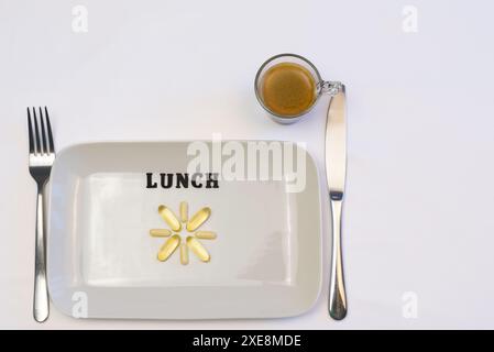 Eine weiße Platte mit Multivitaminen und Omega 3 auf einer weißen Tischdecke mit einer Tasse Kaffee. Messer und Gabel. Kopierbereich. Blick von oben Stockfoto