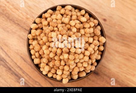 Schüssel mit kleinen kugelförmigen Zimt Toast gewürzten Frühstückszerealien auf einem hölzernen Küchentisch Stockfoto