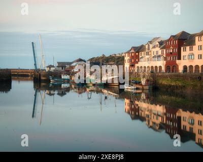 Während die Dämmerung über dem alten Hafen von Maryport fällt, fungieren die ruhigen Meere als Spiegel für die funktionierenden Fischerboote Stockfoto