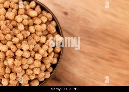 Schüssel mit kleinen kugelförmigen Zimt Toast gewürzten Frühstückszerealien auf einem hölzernen Küchentisch Stockfoto