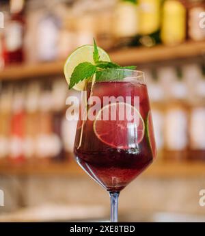 Kalter rosafarbener Cocktail mit frischer Grapefruit, Limette und Eiswürfeln auf dem Restauranttisch Stockfoto