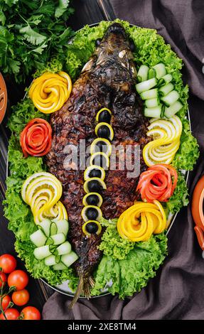 Gebackener Karpfen mit Gemüse in einer Auflaufform auf dem Tisch Stockfoto