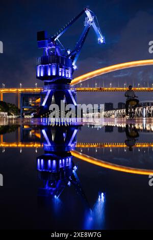 Ein beleuchteter Kran und eine Brücke zur blauen Stunde in Shanghai, China Stockfoto