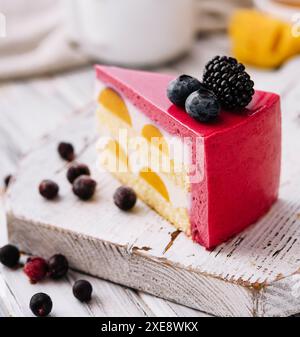 Ein Stück eines rosafarbenen Erdbeerkäsekuchens, serviert mit frischen Beeren auf einer weißen Tafel Stockfoto