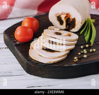 Hackbraten in Scheiben mit Füllung und Tomaten auf einem Schneidebrett Stockfoto