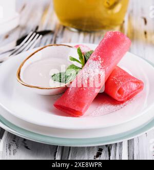 Gerollte Himbeerpfannkuchen mit Sauerrahm für Kinder Stockfoto