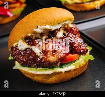 Appetitliche knusprige Hähnchenburger auf schwarzen Tellern Stockfoto