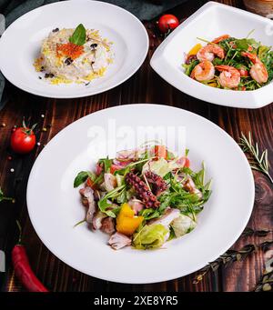 Verschiedene Salate in weißen Tellern auf einem Holztisch Stockfoto