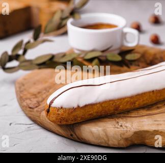 Glasiertes Eclair-Dessert mit Kaffee auf Holz Stockfoto