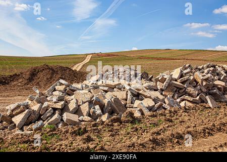 Ablagerung von Betonschutt auf dem Boden in Weinbergen und Natur mit bewölktem Himmel. Großer Stapel Stockfoto