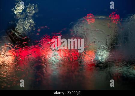 Abstraktes, durch Regen verzerrtes Licht auf der Windschutzscheibe des Autos Stockfoto
