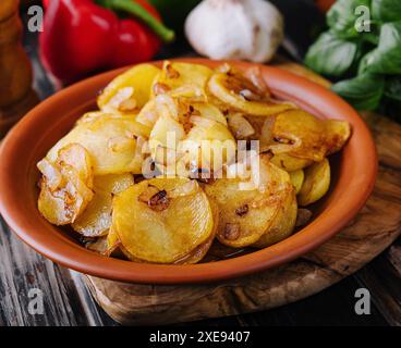 Gebratene Kartoffeln mit Zwiebeln auf Holztablett Stockfoto