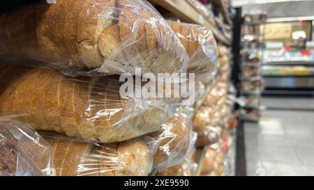 Eine Nahaufnahme der verpackten Brotlaibe, die auf einem Regal in einem Lebensmittelgeschäft gestapelt sind Stockfoto