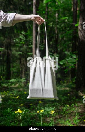 . Modell der Tragetasche aus natürlichem Canvas. Totebag in der Hand, grüner Naturhintergrund, sonniger Sommertag... Stockfoto
