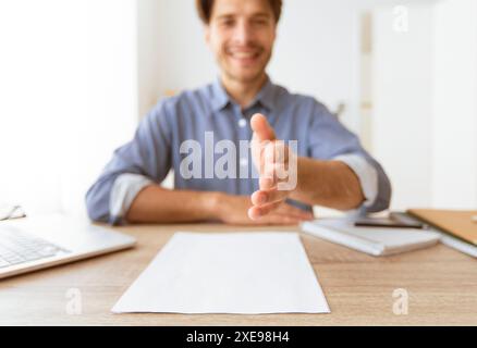 Mann bietet Handshake am Schreibtisch an Stockfoto