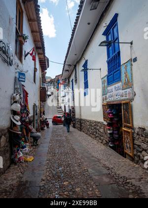 Cusco, Perú; 9. August 2023: Geschäfte in einer Fußgängerzone der Kolonialstraße mit Steinböden, engen und weiß bemalten Häusern Stockfoto