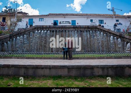 Cusco, Peru – 9. August 2023: Schwarzhaarige Frau posiert mit ihrem Vater vor einem Brunnen in Barrio de San Blas Stockfoto