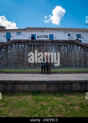 Cusco, Peru – 9. August 2023: Schwarzhaarige Frau posiert mit ihrem Vater vor einem Brunnen in Barrio de San Blas Stockfoto