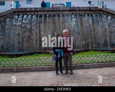 Cusco, Peru – 9. August 2023: Schwarzhaarige Frau posiert mit ihrem Vater vor einem Brunnen in Barrio de San Blas Stockfoto