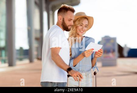 Glückliches Paar an der Bordkarte Kontrolle Abfahrtszeit suchen Stockfoto