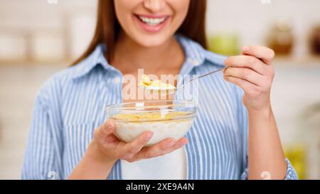 Mädchen essen Joghurt mit Flocken zum Frühstück Stockfoto