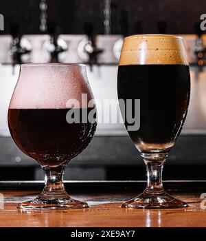 Schwarzes Craft-Bier in Gläsern auf dem Tisch im Pub-Innenraum Stockfoto