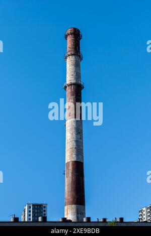 Der Kamin des Kesselhauses erhebt sich über den Gebäuden gegen den blauen Himmel. Stockfoto