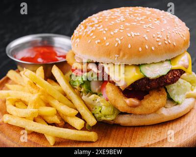 Saftiger Burger mit Zwiebelringen und Pommes frites Stockfoto