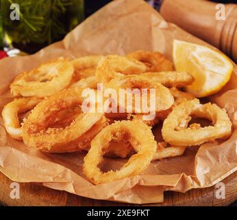 Im Ofen gebackene, panierte Calamari-Ringe, serviert mit Zitrone Stockfoto