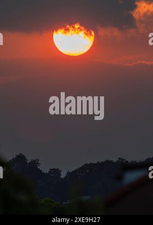 Wimbledon, London, Großbritannien. Juni 2024. Nach einem Tag, an dem die Temperaturen 30 Grad erreichten, untergeht die Sonne hinter niedriger Wolke im Südwesten Londons. Quelle: Malcolm Park/Alamy Live News Stockfoto
