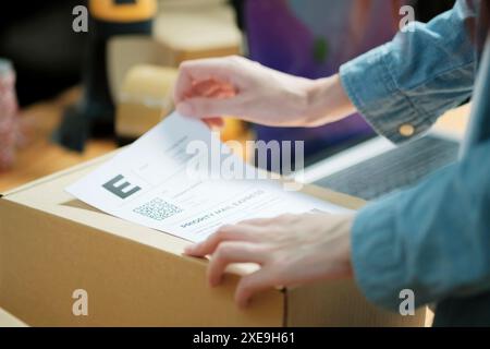 Versandaufkleber an ein Paket anhängen Stockfoto