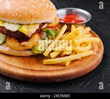 Saftiger Burger mit Zwiebelringen und Pommes frites Stockfoto