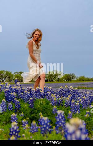 Ein schönes Brünette Model posiert in Einem Feld mit Bluebonnet-Blumen in Einem Texas Prarie Stockfoto