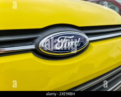 Kiel, Deutschland - 26. Juni 2024: Das Logo des Automobilherstellers Ford auf der Vorderseite eines neuen gelben Autos Stockfoto